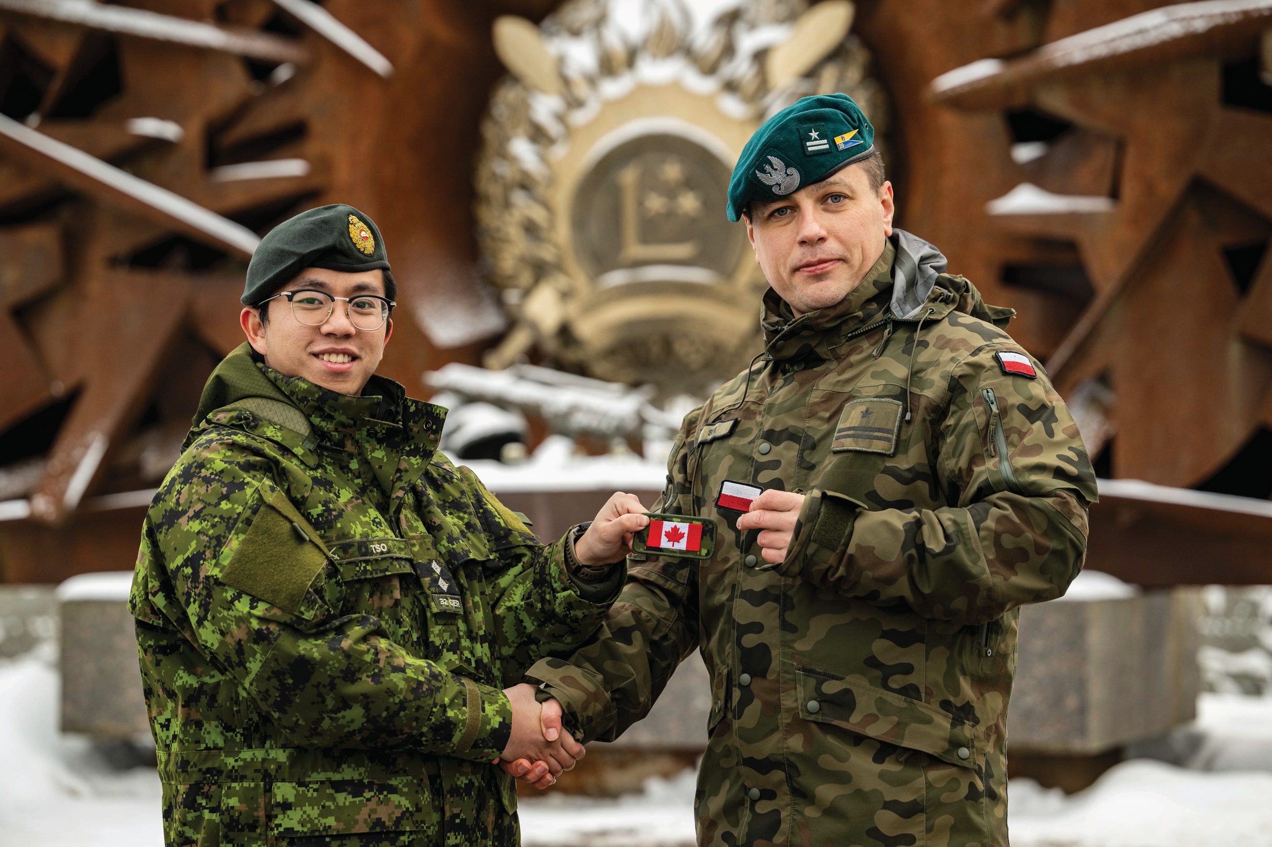 Lt. Samson Tso, an Engineer Officer, and Maj. Tomasz Sek of NATO enhanced Forward Presence Battle Group Latvia, exchange national flag patches before the end of their rotation at Camp Ādaži, Latvia, on 07 December 2023.